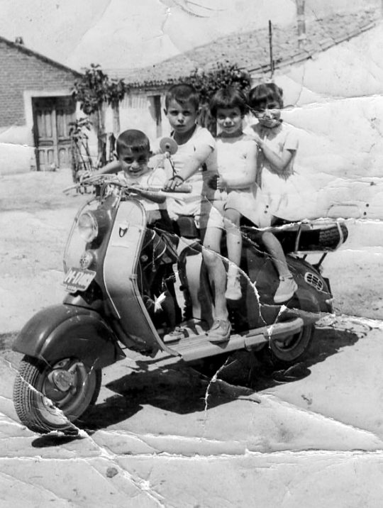 1955 - Un grupo de niños encima de una moto en la Calle Mayor